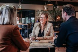 Drie collega's van Rochewood in gesprek aan een vergadertafel met een glas water in de voorgrond