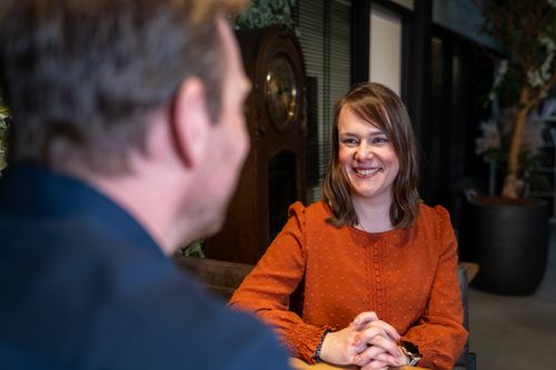 Twee collega's in gesprek aan een vergadertafel in een moderne kantoorruimte