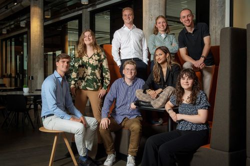 Een groep van acht trainees van het risk traineeship VNAB 2024 in een moderne kantooromgeving