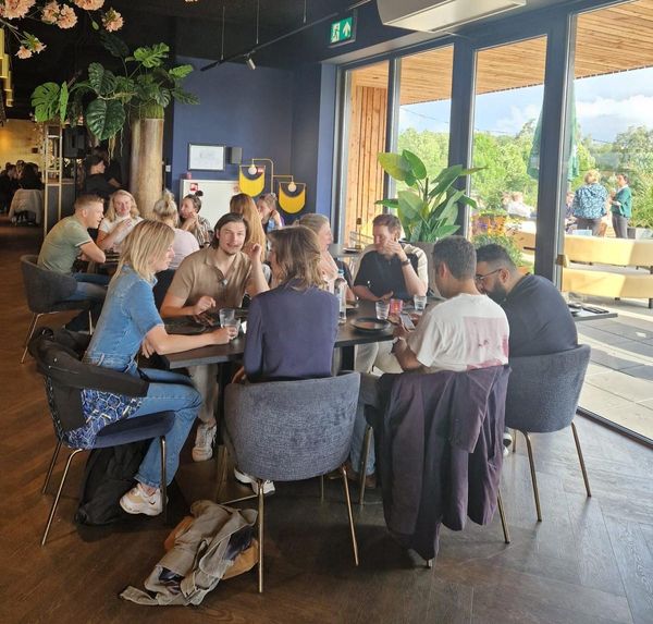 Collega's zitten met elkaar aan tafel Bij Chi Chi The Golf Venue in Utrecht
