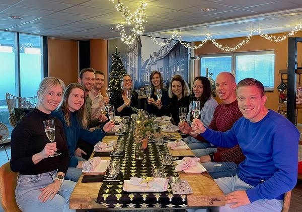 Collega's van Rochewood proosten in een kantooromgeving in kerstsferen