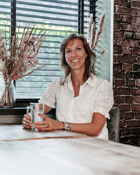 Daphne Voets zit aan tafel met een kop thee