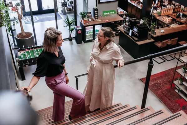 Twee collega's van Rochewood staan op een trap in een moderne kantooromgeving