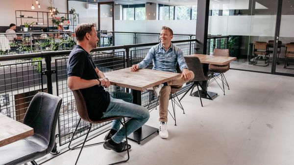 Twee collega's in gesprek in een moderne kantoorruimte
