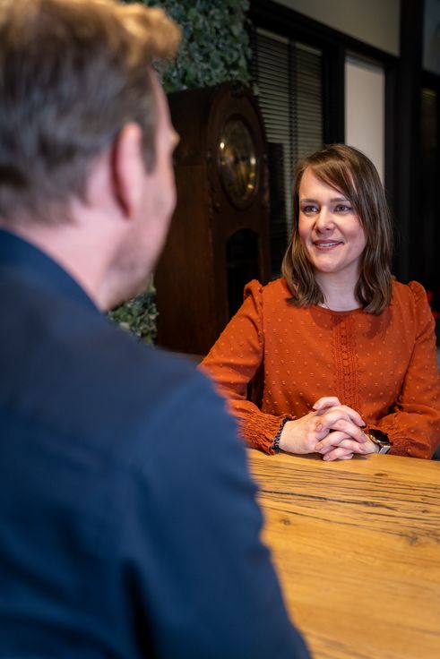 Twee collega's in gesprek aan een vergadertafel in een moderne kantoorruimte