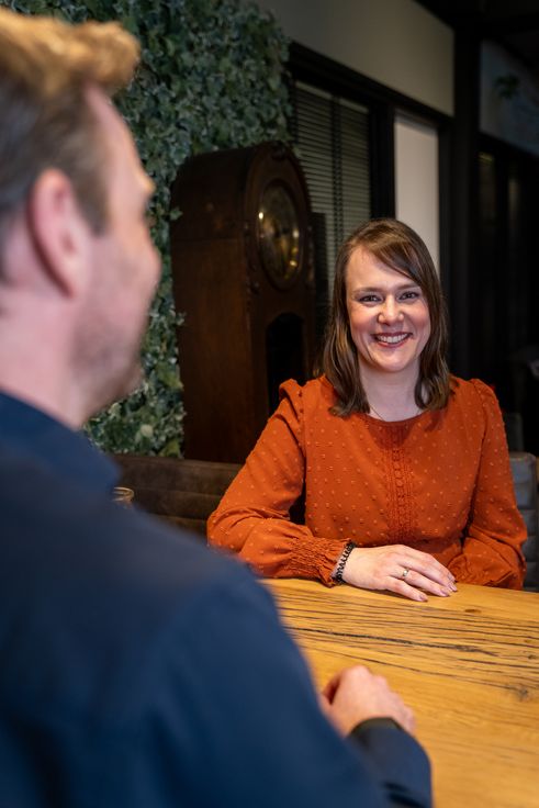 Twee collega's in gesprek aan een vergadertafel in een moderne kantoorruimte