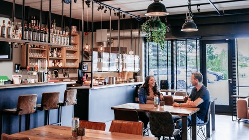Twee collega’s van Rochewood in gesprek aan een tafel in de lunchruimte