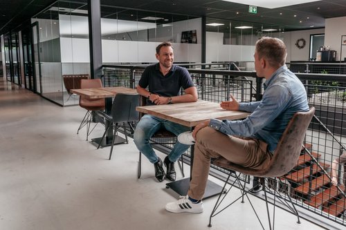 Twee collega's in gesprek in een moderne kantoorruimte