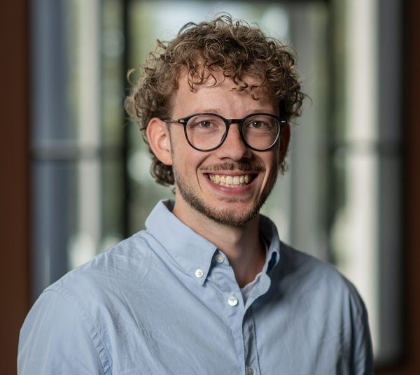 Lachende trainee in een blauw overhemd, deelnemer van het VNAB Risk Insurance Traineeship