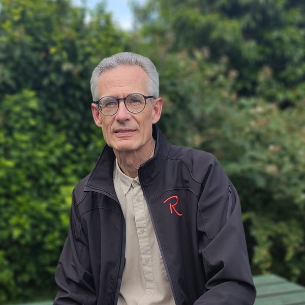 Eric Zuijdervelt - collega Acceptant Schadeverzekeringen bij Rochewood. Hij zit op een tuintafel met op de achtergrond bomen en planten.
