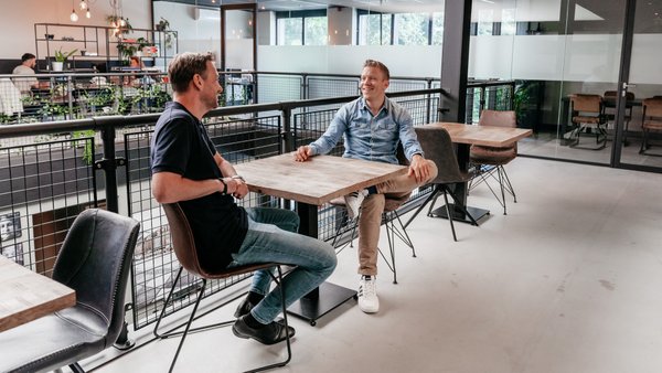 Twee collega's in gesprek in een moderne kantoorruimte